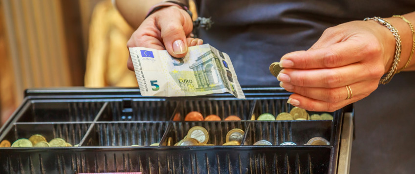 Pārdevējs kasē liek eiro banknotes, ilustratīvs attēls